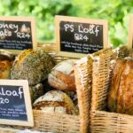 a close-up of crates with different artisanal loaf of breads, with black board which show the prices for each in South African Rands.
