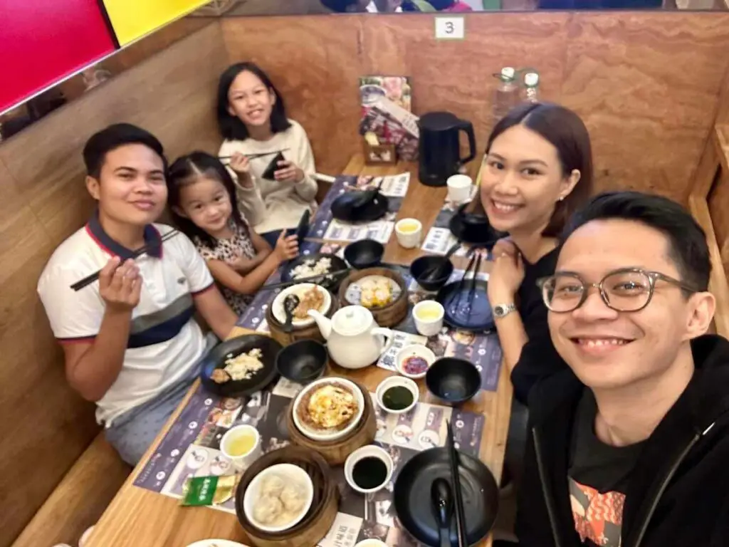 A group of people gathered around a table with a lot of small dishes on it, smiling at the camera.