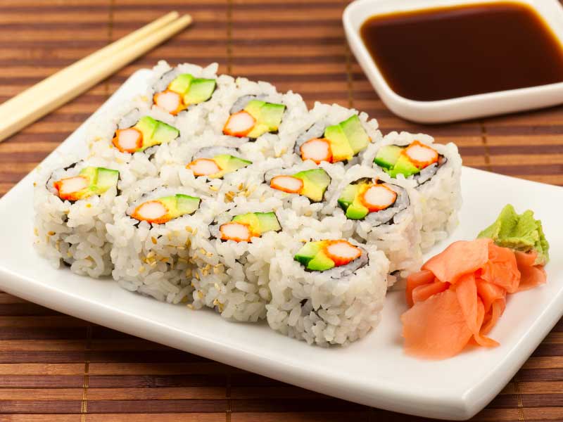 A white rectangular platter with California sushi rolls on it.