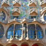 The facade of Casa Batllo, with odd shaped windows and mosaic covering the walls.