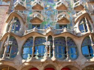 The facade of Casa Batllo, with odd shaped windows and mosaic covering the walls.