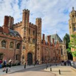 A beautiful building in Cambridge. The entrance is through a tower with four smaller towers on the top. The facade is made from reddish bricks.