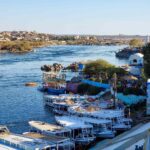 A view of the dock in the Nubian village in Aswan. There are boats anchored just in front of a staircase leading to the village. Behind, there is the water of the Nile River.