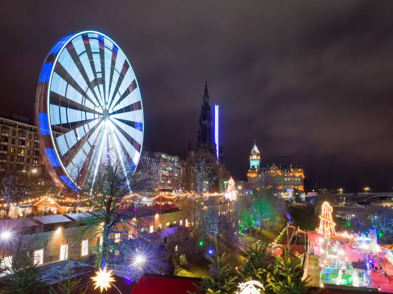 The Christmas market in Edinburgh, at night, with a ferris wheel on the left.