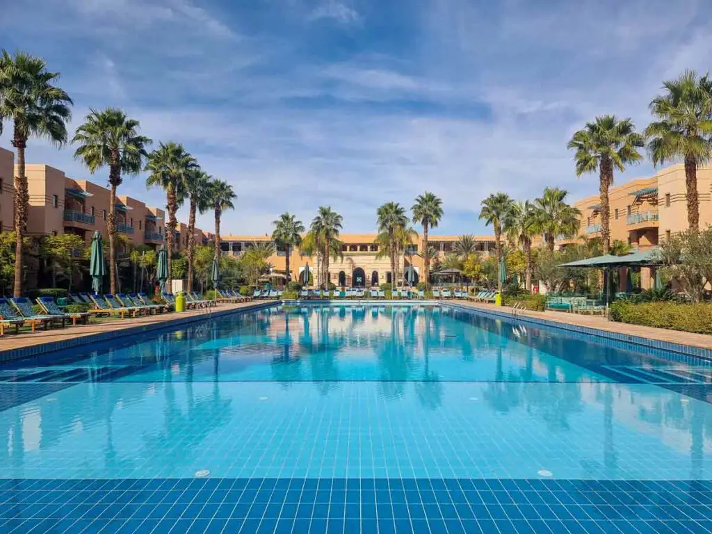 The large pool surrounded by palm trees, in the interior garden of the hotel.