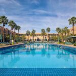 The large pool surrounded by palm trees, in the interior garden of the hotel.