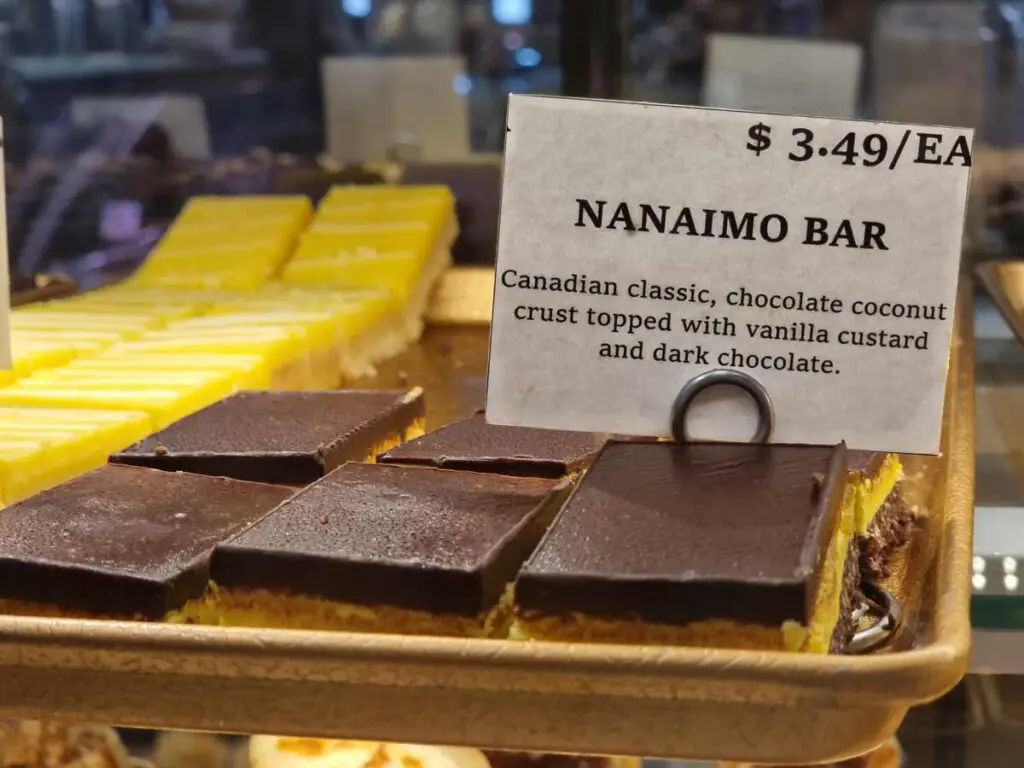 Nanaimo bars, a typical Vancouver Island food, on a golden tray, in the bakery, one next to each other. The price advertised is $3,49 each.
