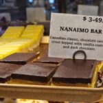 Nanaimo bars, a typical Vancouver Island food, on a golden tray, in the bakery, one next to each other. The price advertised is $3,49 each.