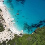 A secluded beach bordered by lush green vegetation. The photo has been taken from above.