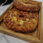 Two round fried patties on a wooden board