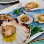 A platter with scallops served in their own shells
