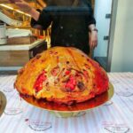 A sweet bread in the shape of half a football filled with pink praline. It sits in the window of a bakery