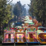 Traditional boats, very colourful, painted in vibrant colours, one next to each other, on the river in Xochimilco