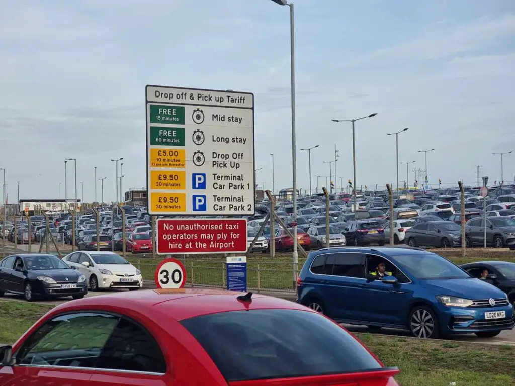 A photo of the land car park in Luton airport, with the fees associated with it. The car park is full of cars.
