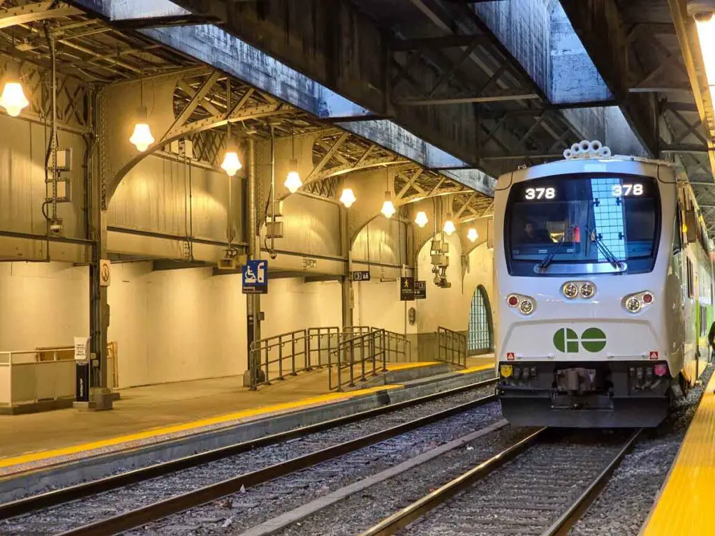 A Go train, which is white and has Go written on the front with green, on the platform, at Union station in Toronto.
