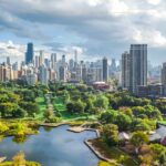 An aerial photo of Chicago on a cloudy day. In the background you can see tall sky scrapers. In the foreground there is a large park with a lake in the middle.