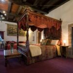 A medieval room inside a castle, with a four poster bed with a canopy on the top.
