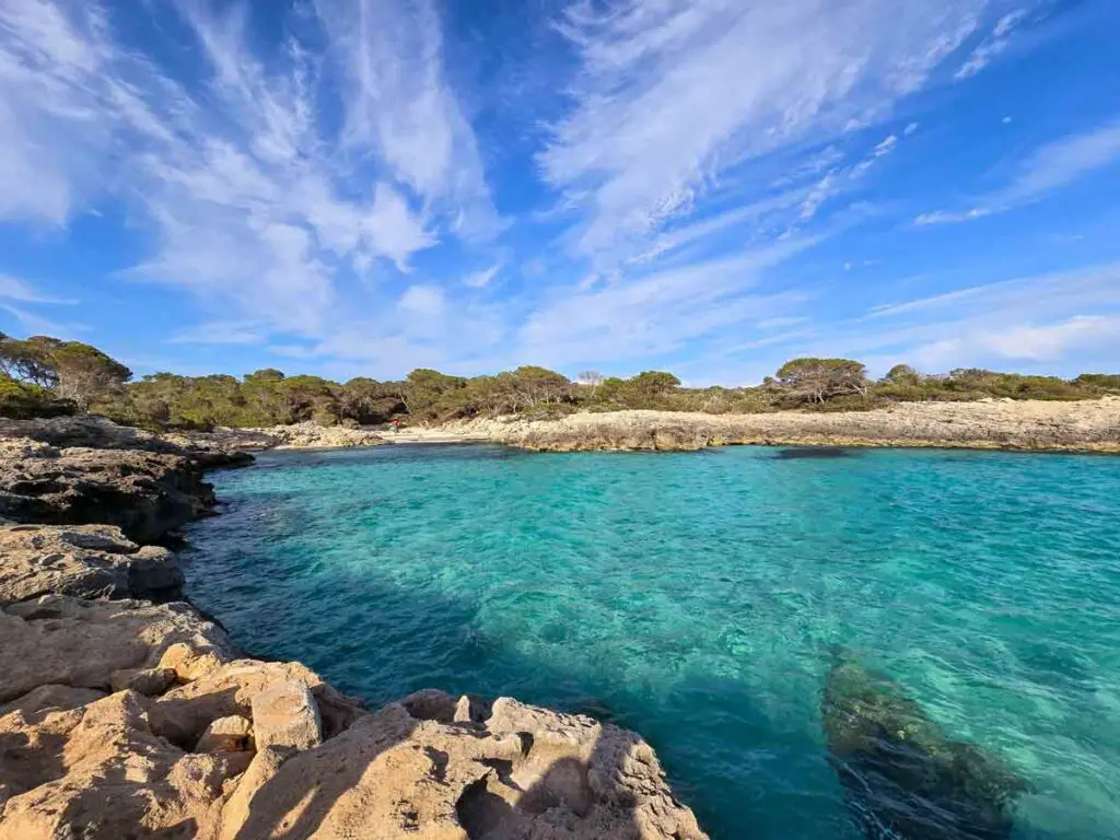 A small bay with turquoise waters, surrounded by cliffs.