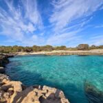 4 Days in Menorca: A Unique Off the Beaten Path Itinerary A small bay with turquoise waters, surrounded by cliffs.