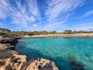 A small bay with turquoise waters, surrounded by cliffs.