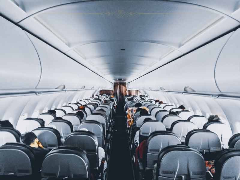 The interior of a plane, photographed from the middle of the aisle towards the front.