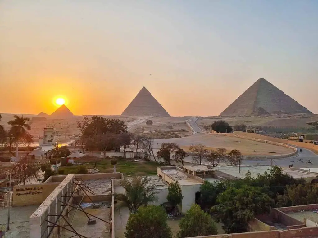 The pyramids at sunset. The sun is behind the top of the third pyramid, on the left of the photo.