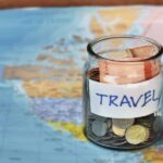A jar sitting on a world map filled with different currencies and coins.