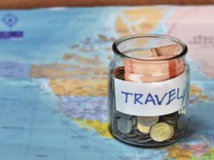 A jar sitting on a world map filled with different currencies and coins.