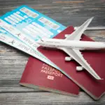 A plane over two passports with two boarding passes in them.