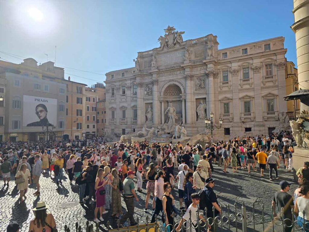 Fontana di Trevi on a sunny day, with a lot of people in front of it.