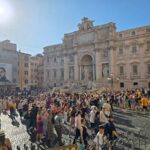 Fontana di Trevi on a sunny day, with a lot of people in front of it.