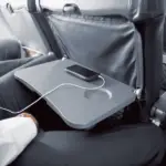 A close-up of a man sitting in the middle seat, with the tray down and a phone on the tray.