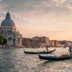 Two gondolas on the Grand Canal in Venice, at sunset. Behind, you can see the cupola of the Academia building