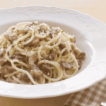 A deep white plate filled with carbonara spaghetti