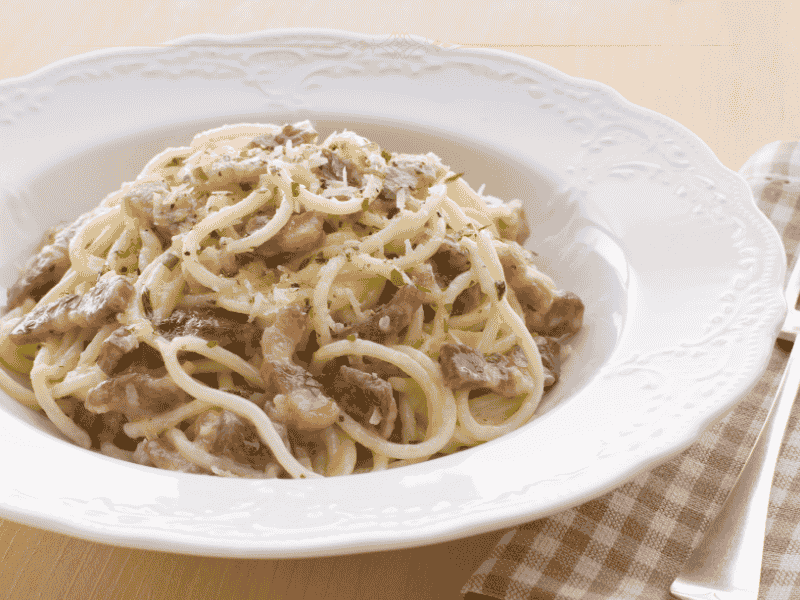 A deep white plate filled with carbonara spaghetti