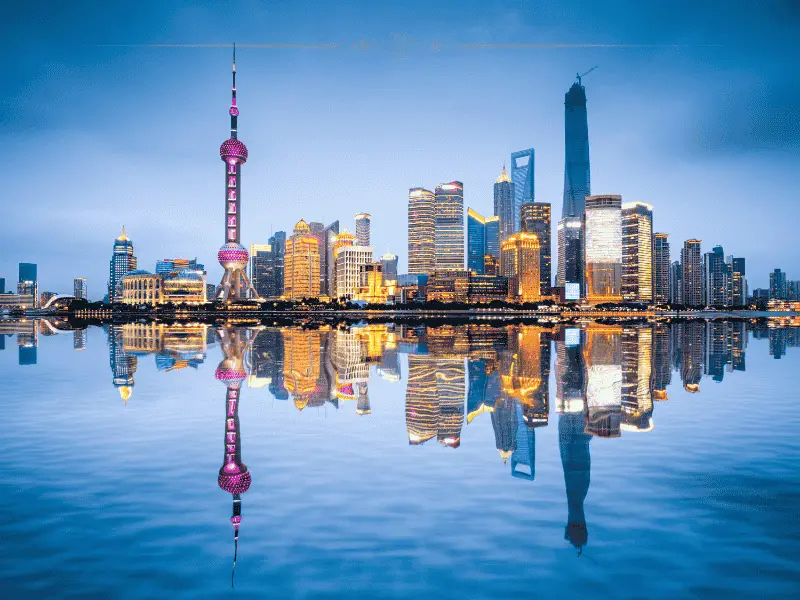 A photo of sky scrapers reflecting in the water below them, at dusk.