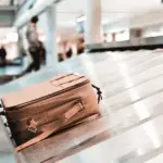 A brown suitcase on the conveyor belt at the airport.