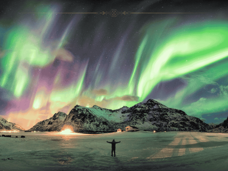 A man holding his hands open for the Northern lights in front of him which light the sky green.