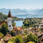A picturesque town on the shore of a lake, with a mountain background