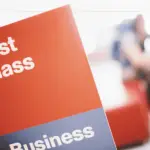 A red sign with First class written on the top in white letters, with a grey bottom with business written on it in white letters.