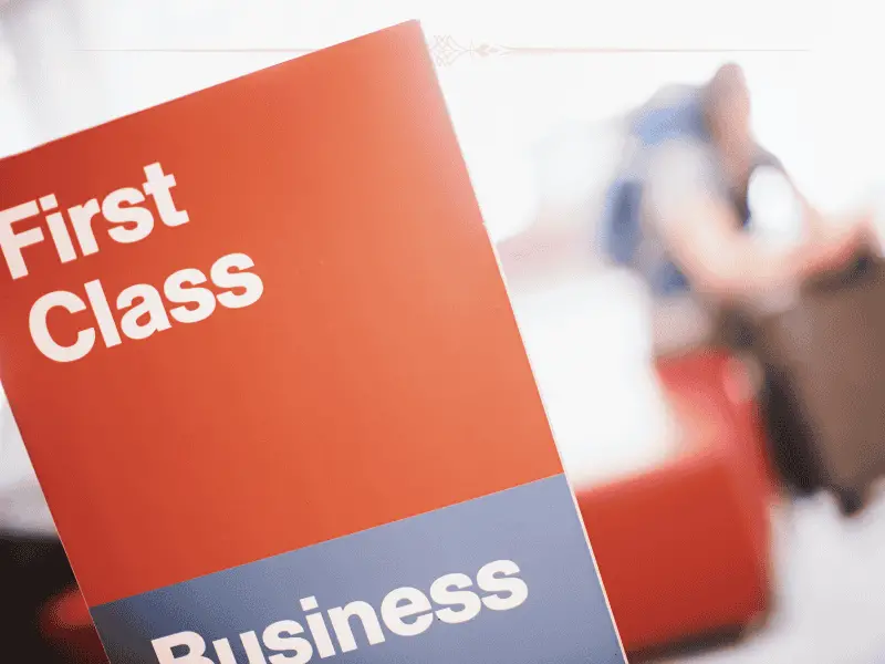 A red sign with First class written on the top in white letters, with a grey bottom with business written on it in white letters.