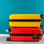 A bright yellow bag on top of a bright red one, photographed against a blue background.