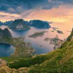 A view over fjords in Norway, taken at sunrise. The sky is pink.