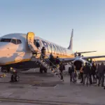 A plane on the tarmac, with people using both doors to board.