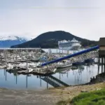 A small harbour with a cruise ship in the background on a cloudy day