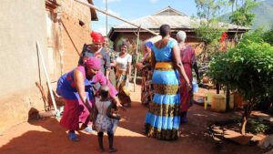 A group of women dressed in colourful clothes, dancing in a garden in a village in Tanzania