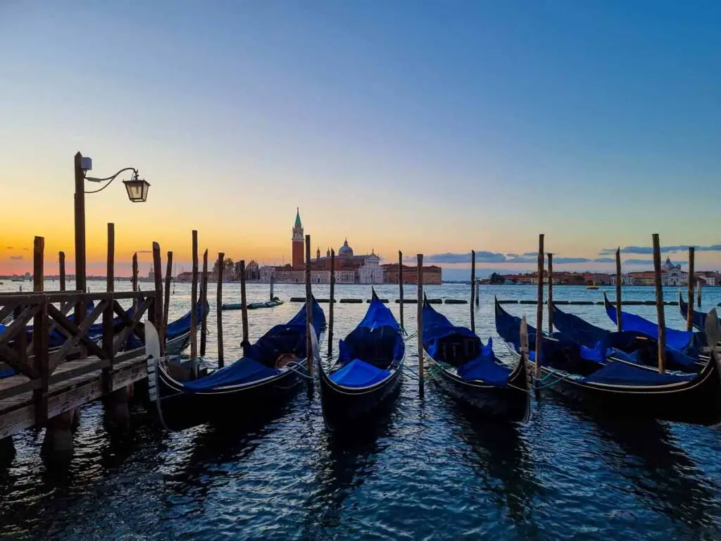 Gondolas one next to each other, at sunrise, on the Grand Canal in Venice