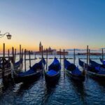 Gondolas one next to each other, at sunrise, on the Grand Canal in Venice
