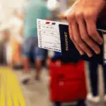 A close-up of a hand holding a passport with a boarding pass in it.