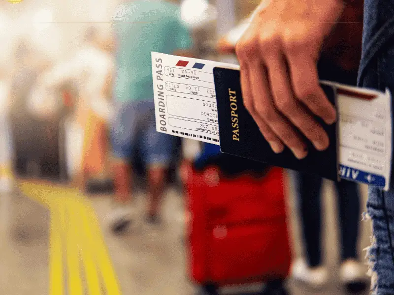 A close-up of a hand holding a passport with a boarding pass in it.